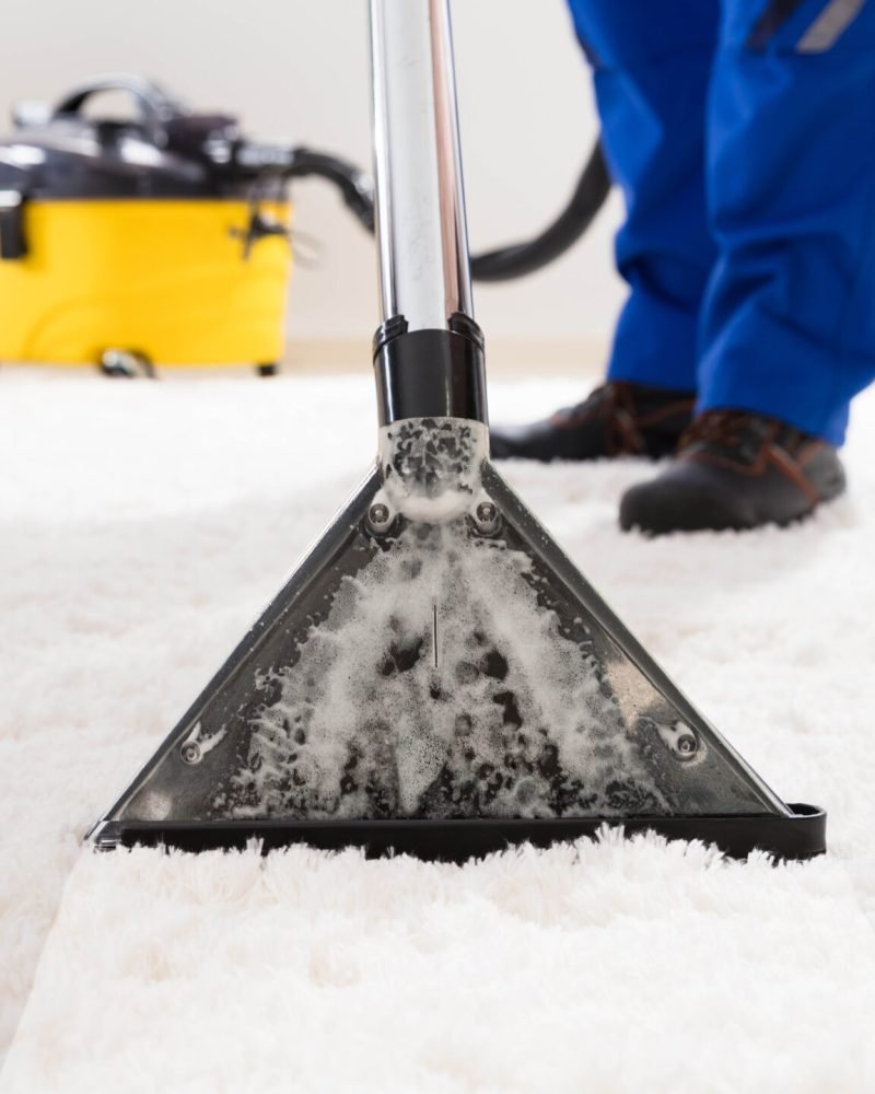 Close-up Of A Janitor Cleaning Carpet With Vacuum Cleaner At Home